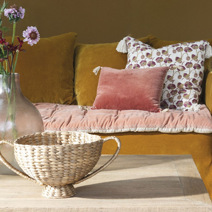 couch with cushion with floral pattern on natural coloured fabric with tassels